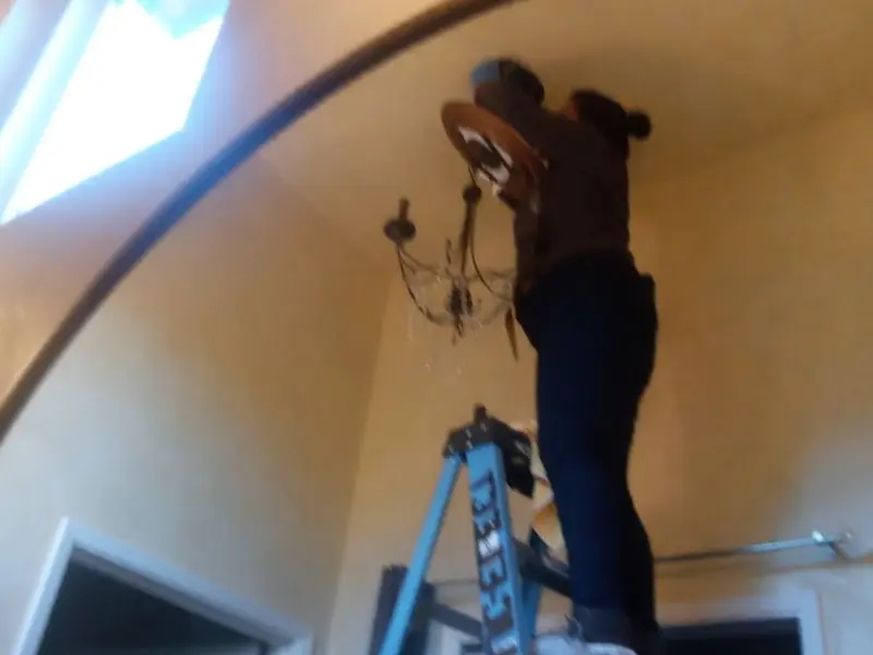 Electrician installing a chandelier in a Tyler residence